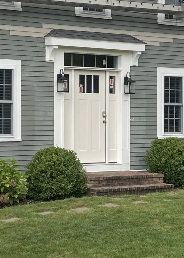 Gray clapboard house with new white entry door and trim