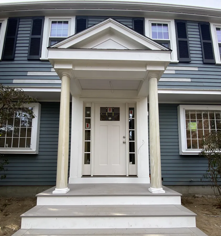 Pedimented portico entry on a navy-shuttered home
